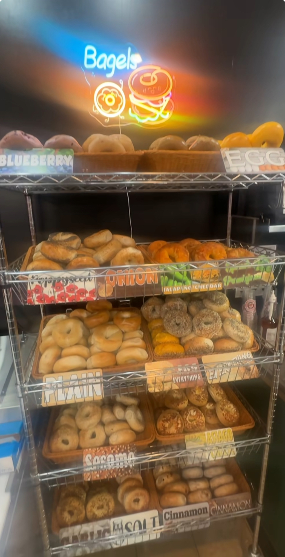 Breakfast Bros bagel display case under the neon Bagels sign