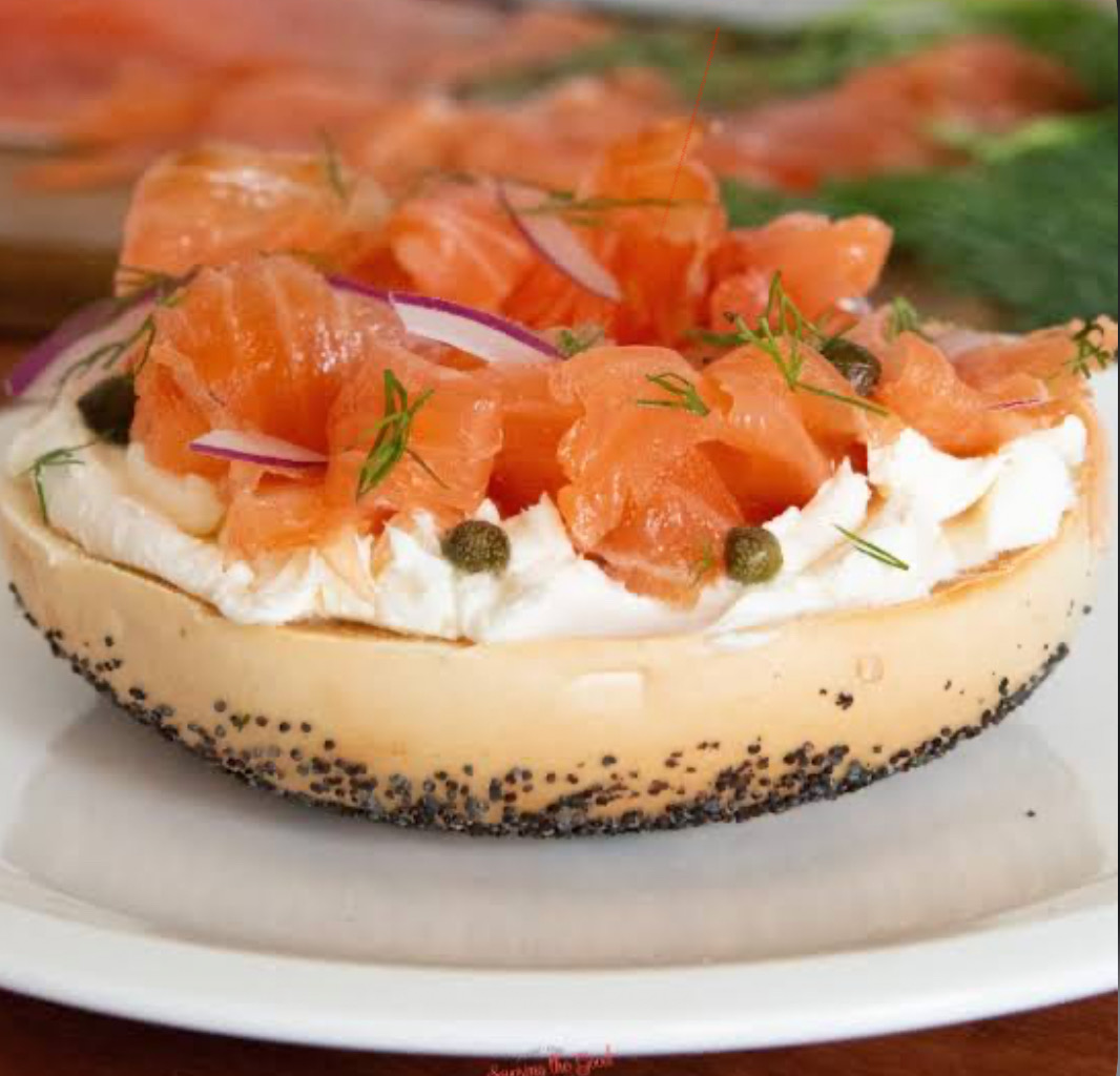 Open-faced poppy bagel piled with lox, cream cheese, capers and red onion