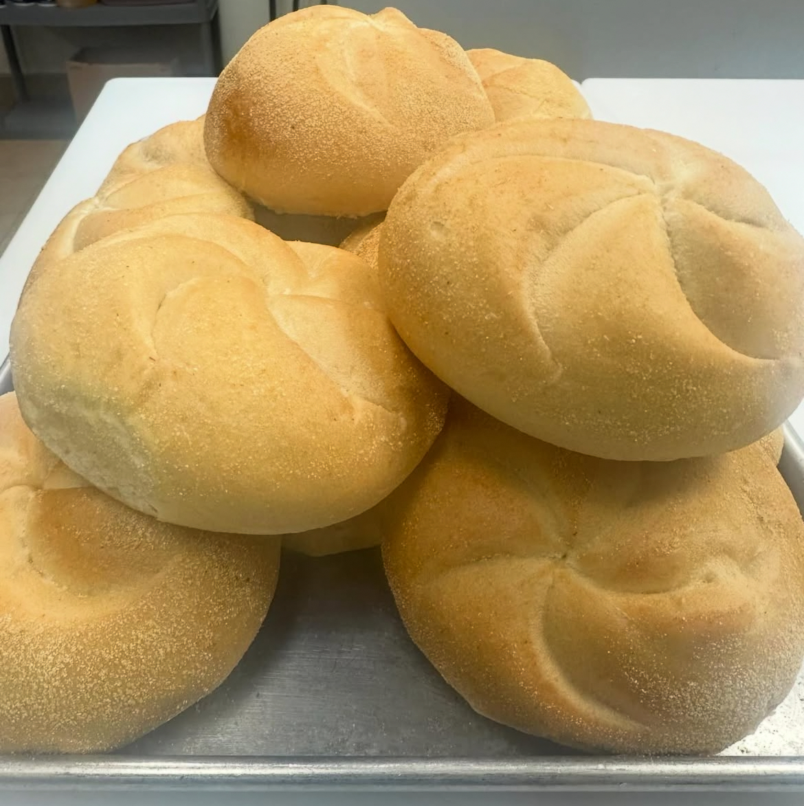 Stack of fresh plain kaiser rolls dusted with flour