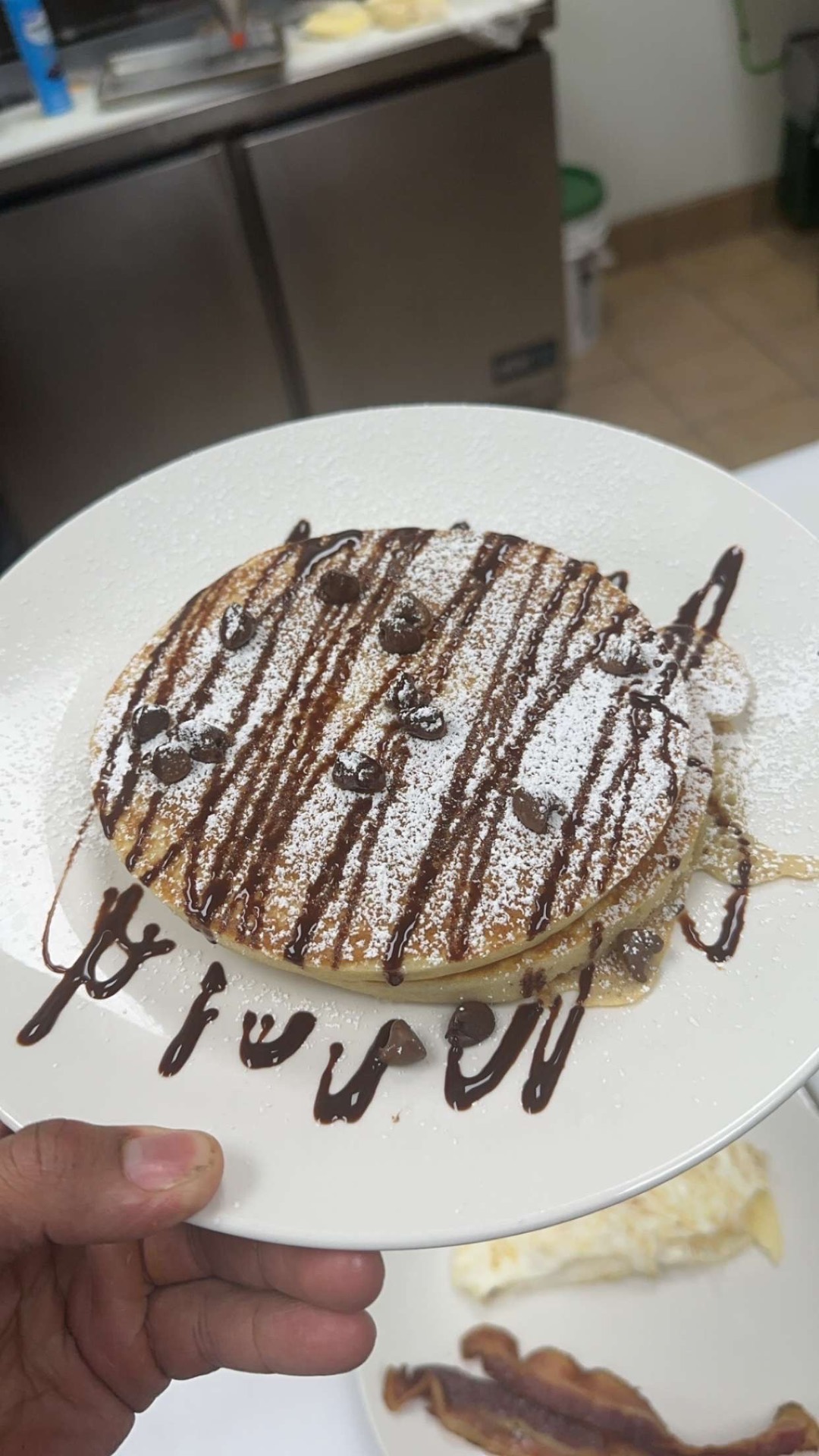 Chocolate chip pancakes with powdered sugar and chocolate drizzle