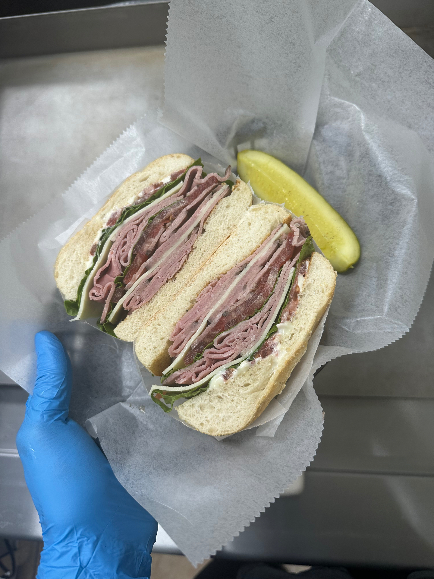 Stacked roast beef sandwich with provolone, lettuce and tomato on a kaiser
