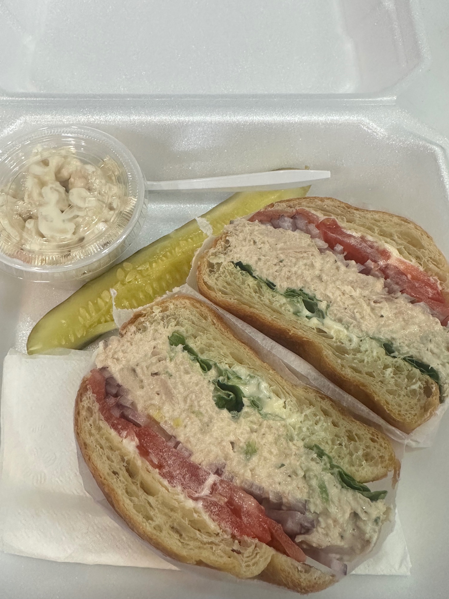 Tuna salad on a flaky croissant with lettuce, tomato and red onion